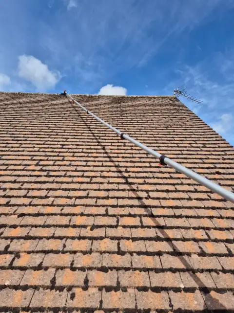 Cleaned clay pantile roof under a blue sky with a pole system resting against it