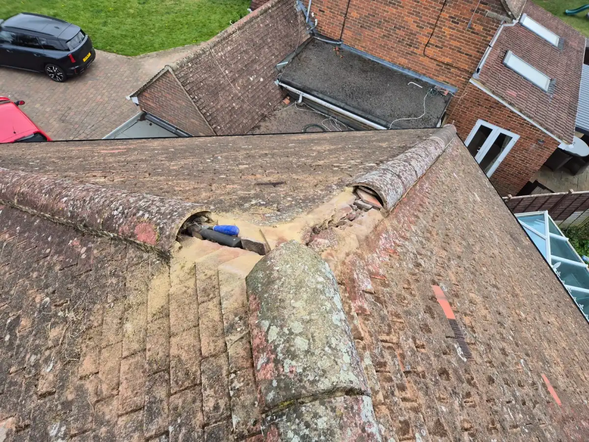 Ridge tile lifted away from a roof showing failed mortar underneath